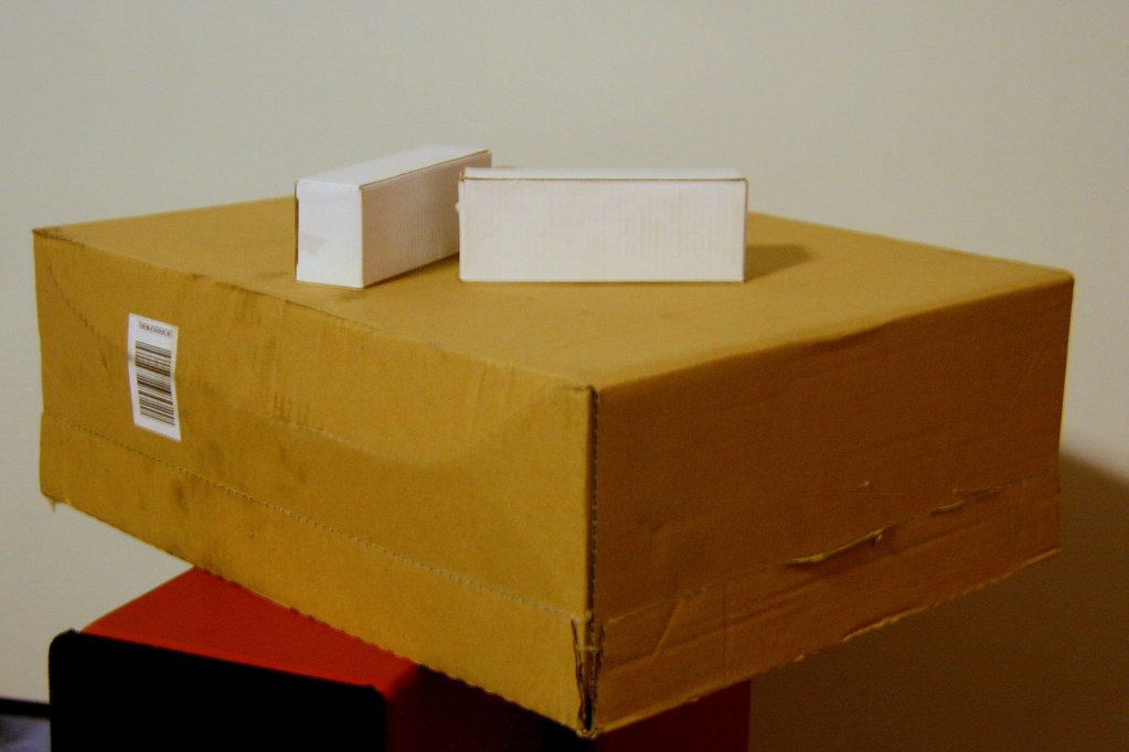 Cardboard shipping box with two small white boxes on top